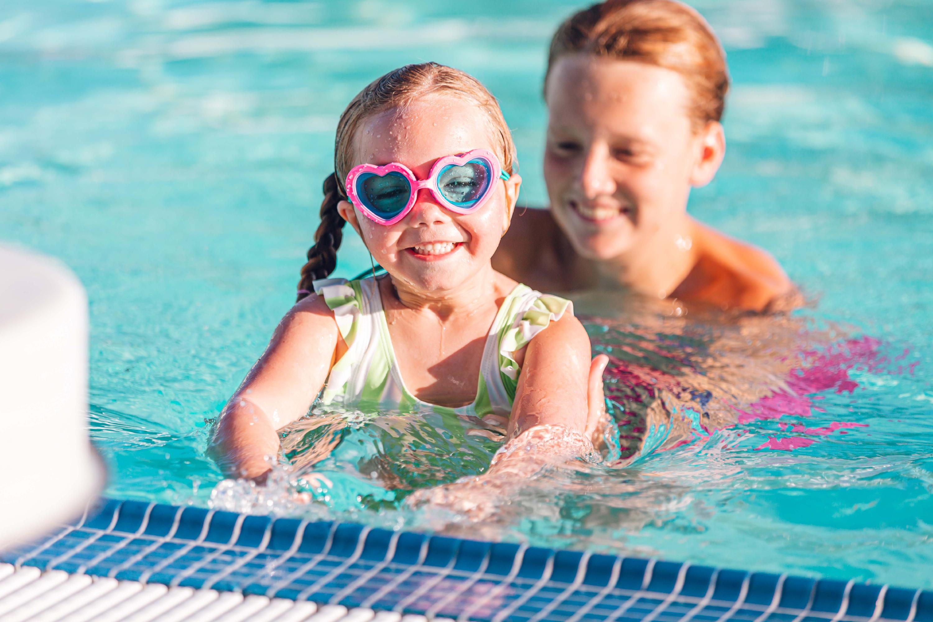 Young girl swimmer in the water, wearing goggles in the shape of hearts
